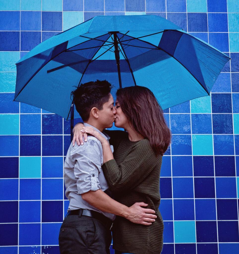 A same-sex couple in front of a blue tiled wall
